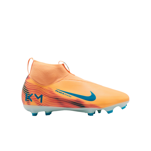 An orange and peach Nike soccer cleat with blue accents, featuring a laceless design, high-top collar, and "KM" logo on the heel, set against a black background.