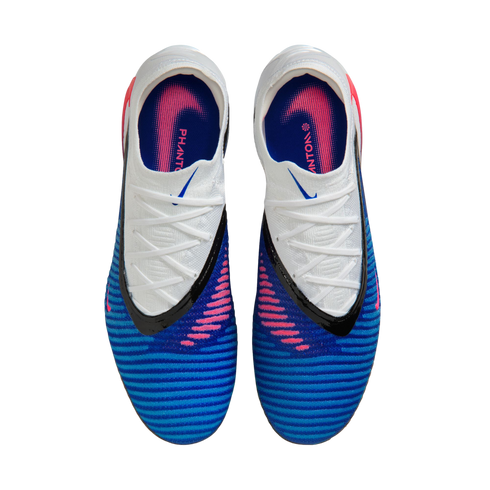 A top-down view of a pair of blue and white Nike Phantom soccer cleats with pink accents and black trim, set against a solid black background.