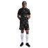 Man in a black patterned Nike soccer uniform with white knee-high socks and black shoes, standing against a plain white background.