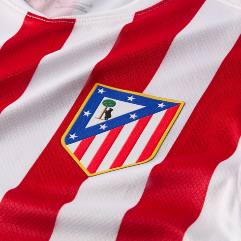 Close-up of the Atlético de Madrid football club crest on a jersey with red and white vertical stripes.