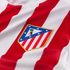 Close-up of the Atlético de Madrid football club crest on a jersey with red and white vertical stripes.