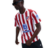 A person in sunglasses wearing a red and white striped Atletico Madrid soccer jersey with Riyadh Air and Kraken sponsors, standing against a white background.