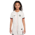 A young girl with curly hair posing in a white Chelsea FC soccer jersey with red and green accents and matching shorts.