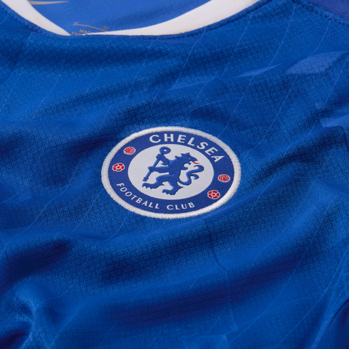 Close-up of the Chelsea Football Club crest embroidered on a textured blue soccer jersey.