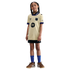 Young girl posing in a gold FC Barcelona Mamba jersey, black shorts, blue socks, and brown sneakers against a black background.