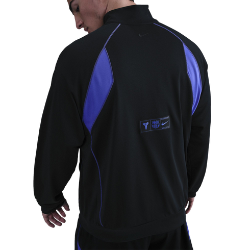 Rear view of a man wearing a black and purple sports jacket with FC Barcelona and Kobe Bryant logos on the lower back.