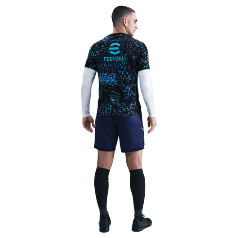 Back view of a man in a black and blue patterned football jersey, navy shorts, and black socks against a white background.