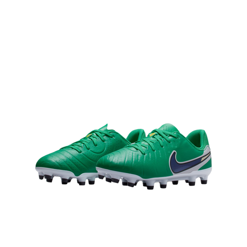 A pair of green Nike kids' soccer cleats with a navy blue swoosh and black studs, set against a plain white background.