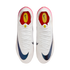 Top-down view of a pair of white Nike soccer cleats featuring iridescent blue swooshes, white laces, and pink heel accents on a plain white background.