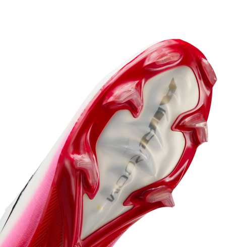 A close-up view of the soleplate of a red and pink Nike soccer cleat, showcasing its sharp red studs and a translucent center featuring 'AIR ZOOM' branding.