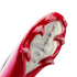 A close-up view of the soleplate of a red and pink Nike soccer cleat, showcasing its sharp red studs and a translucent center featuring 'AIR ZOOM' branding.