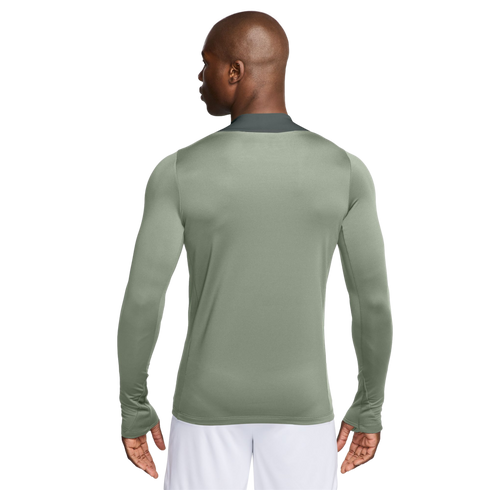 Rear view of a man wearing a sage green long-sleeved athletic shirt with thumbholes and white shorts.