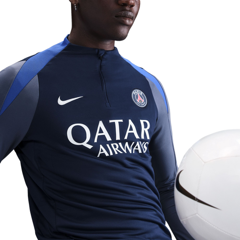 A person wearing a navy Nike PSG training top with "QATAR AIRWAYS" logo, posing with a white soccer ball.