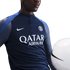 A person wearing a navy Nike PSG training top with "QATAR AIRWAYS" logo, posing with a white soccer ball.