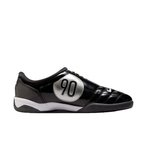 Side profile of a black glossy Nike Total 90 indoor soccer shoe featuring a large silver circular "90" logo and a white midsole.