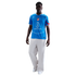 Man in a blue Atletico Madrid soccer jersey and white wide-leg trousers against a black background.