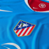 A close-up view of a blue Nike soccer jersey featuring the Atlético Madrid team crest and a red inner collar with a "90" logo.