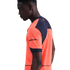 Profile of a man wearing a bright orange and navy blue athletic shirt with "AMBILIGHT tv" on the sleeve, set against a solid black background.