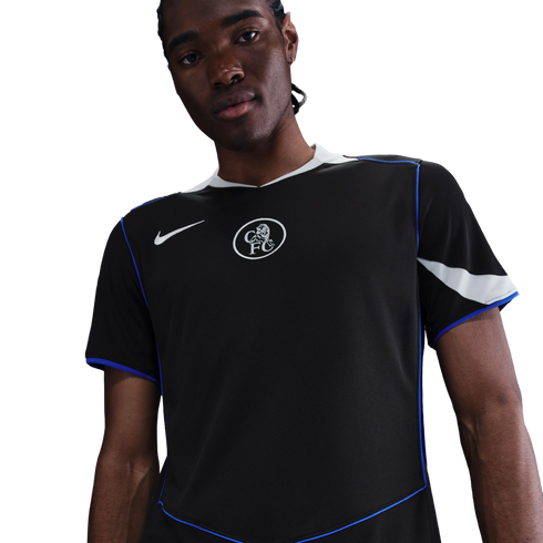 A man in a black Nike Chelsea FC jersey with blue piping and a white crest, against a solid black background.