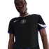 A man in a black Nike Chelsea FC jersey with blue piping and a white crest, against a solid black background.