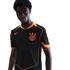 A Black man wearing a black soccer jersey with bright orange trim and a Corinthians crest against a black background.