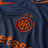 Close-up of a navy blue Inter Milan jersey featuring an orange embroidered crest with two stars, a Nike swoosh, and partial Betsson sponsor logo.