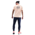 Rear view of a man wearing a peach "BARÇA" t-shirt, navy joggers, and orange sneakers, set against a black background.