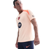 A man wearing a peach Nike FC Barcelona training top and navy shorts, looking off-camera against a black background.