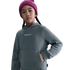 A young girl in a pink knit beanie and a grey Nike "Barça" hoodie looks forward against a solid black background.