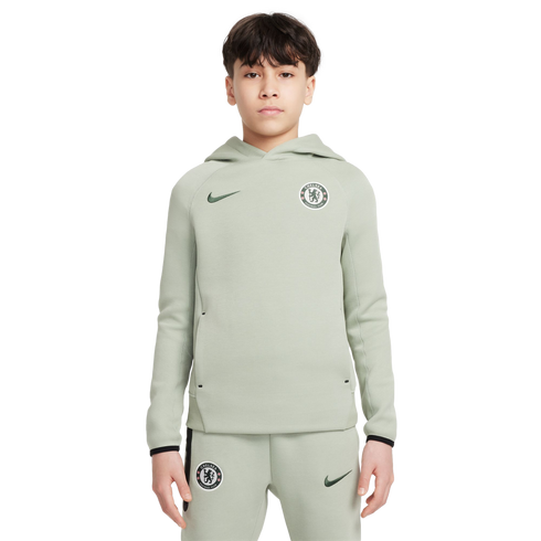 A boy wearing a light green Nike tracksuit with Chelsea FC crests on the hoodie and pants, set against a white background.