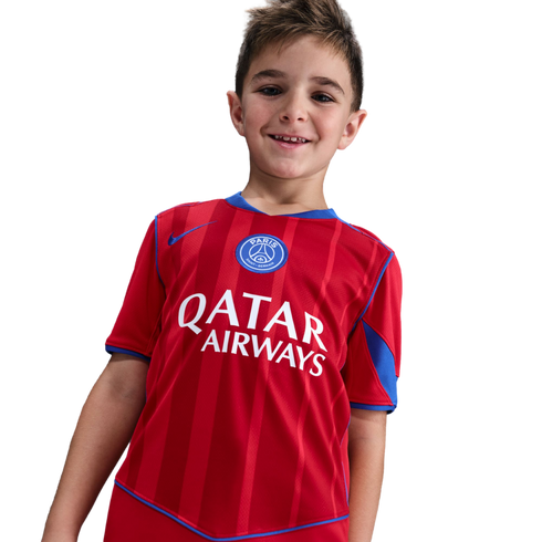 Smiling young boy wearing a red and blue Paris Saint-Germain soccer jersey with a Qatar Airways sponsor logo.