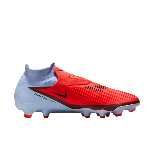 A profile view of a Nike Phantom Flyknit soccer cleat with a vibrant red upper and light blue heel against a black background.