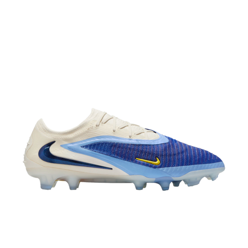 A side-view of a Nike Phantom GX soccer cleat featuring a cream, royal blue, and light blue design with a prominent dark blue swoosh on the heel and a small yellow swoosh.
