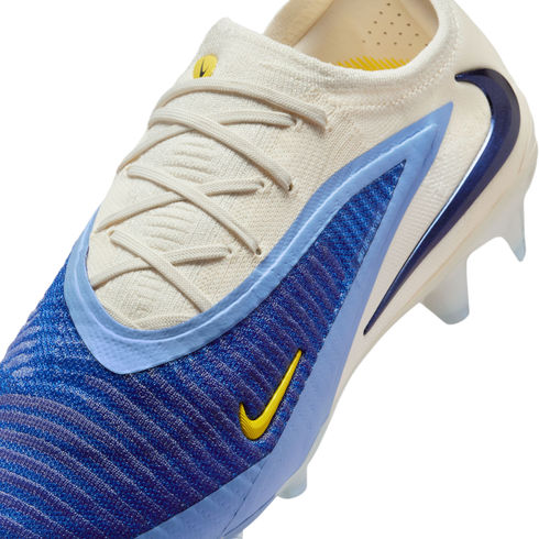 Close-up of a Nike Phantom soccer boot with a cream knit upper, textured blue panels, and a yellow swoosh logo.