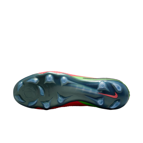 A bottom-up view of a Nike soccer cleat featuring an iridescent dark green soleplate with translucent studs. A small red Nike swoosh is visible near the heel, and the edges of the red and neon green upper are visible against a solid black background.