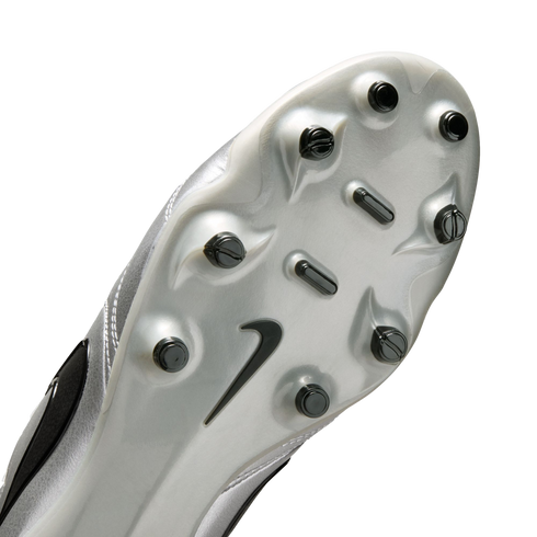 A close-up of the silver soleplate of a Nike soccer cleat, featuring black studs and a black Nike swoosh logo, set against a solid black background.