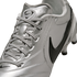 A close-up, angled shot of a metallic silver Nike soccer cleat featuring black swooshes and silver laces against a black background.
