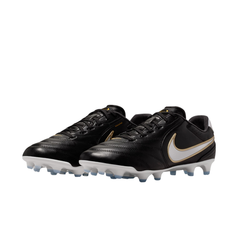 Black Nike leather soccer cleats with white and gold swooshes, featuring white soles and light blue studs, presented against a solid black background.