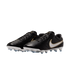 Black Nike leather soccer cleats with white and gold swooshes, featuring white soles and light blue studs, presented against a solid black background.