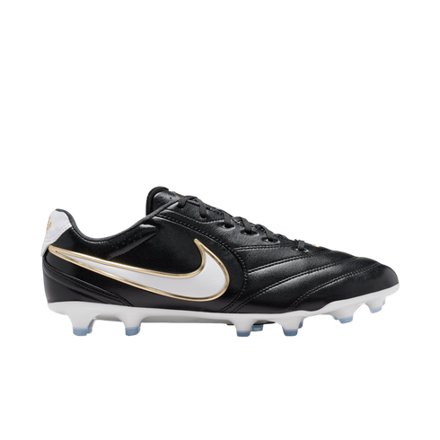 Profile view of a black leather Nike soccer cleat with a white and gold swoosh, white sole plate, and light blue studs, isolated on a black background.