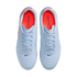 A top-down view of a pair of light blue Nike Tiempo Gato indoor soccer shoes with bright orange insoles, set against a solid black background.