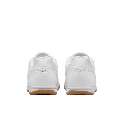 Rear view of a pair of white athletic shoes with tan gum soles, isolated against a black background.