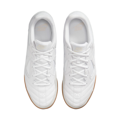 Top-down view of a pair of white Nike sneakers with gum soles, positioned against a solid black background.