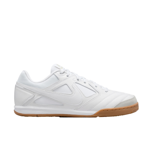 Profile of a white Nike indoor soccer shoe with a mesh and leather upper and a gum rubber outsole, set against a black background.