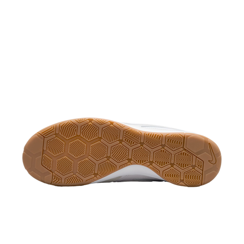 Underside of a gum rubber Nike shoe outsole with a hexagonal traction pattern against a solid black background.