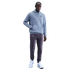 A man models a light blue Nike Spurs hoodie, dark purple sweatpants, and white sneakers against a black background.