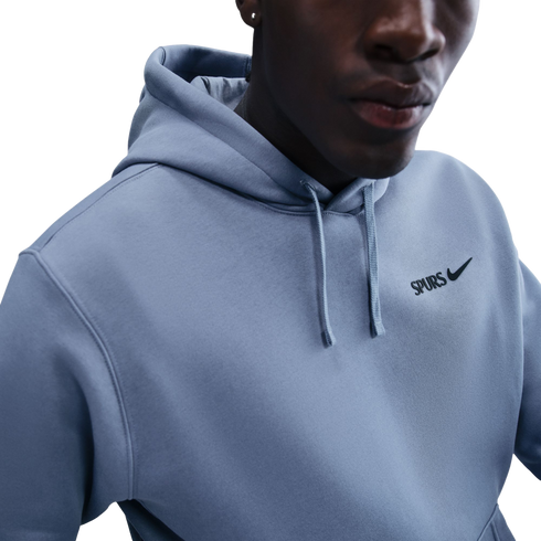 A close-up shot of a person wearing a light blue Nike hoodie with "SPURS" printed on the chest.