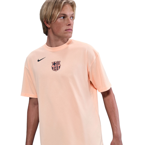 A young man with blond hair wearing a peach-colored FC Barcelona Nike t-shirt, looking to the side against a solid black background.