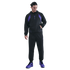 A man wears a black and purple Nike Kobe Bryant x FC Barcelona tracksuit and purple sneakers, standing against a black background.