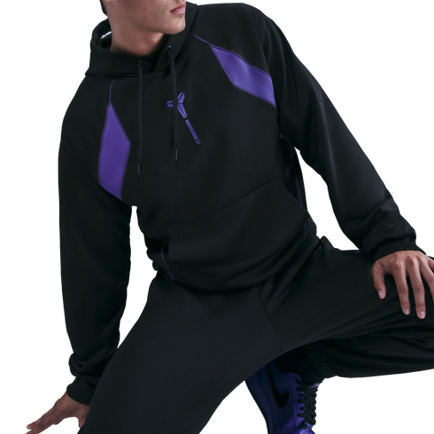 A person posing in a black Kobe Bryant x FC Barcelona hoodie with purple accents and matching black pants.